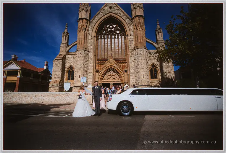 Cristina and Mitch emerge from St Patrick's grand stone facade beside a waiting white stretch limousine
