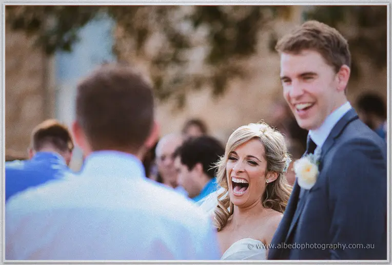 Cristina laughs mid-greeting outside the basilica while guests mill in soft afternoon light
