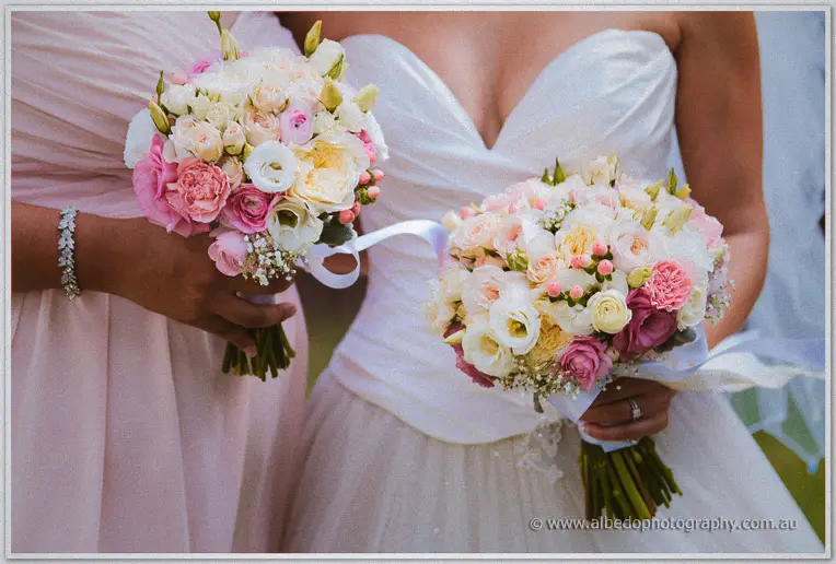 Close-up of Cristina's pastel rose bouquet beside a bridesmaid's blush posy, ribbons trailing
