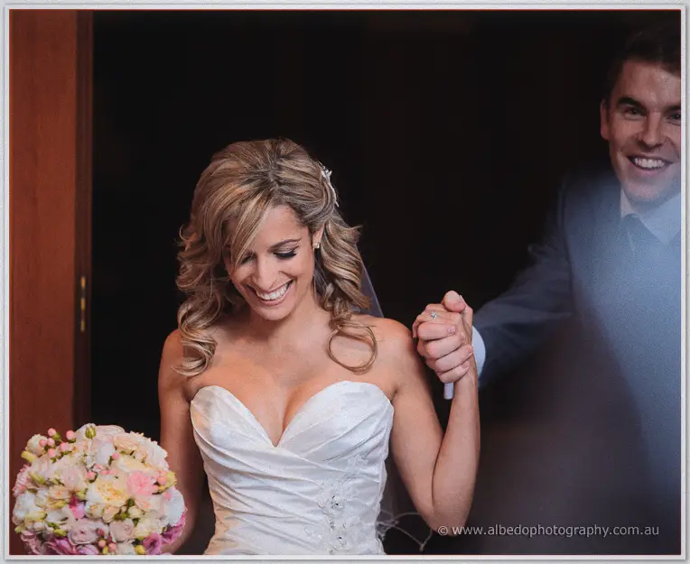 Cristina beams in her strapless gown clutching pastel roses as Mitch grins and raises her hand behind