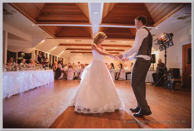 Cristina and Mitch share their first dance on the timber floor as seated guests watch under fairy lights