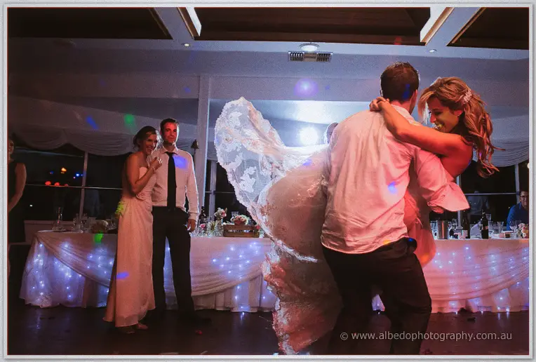 Groom spins his laughing bride until her lace veil swirls out across the disco-lit dance floor