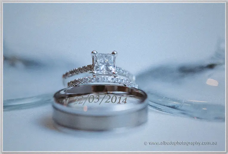 Princess-cut diamond ring and engraved wedding band stacked in cool blue close-up light