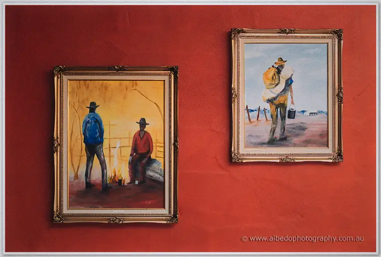 Two framed paintings of outback drovers hang on the terracotta wall of the family home.