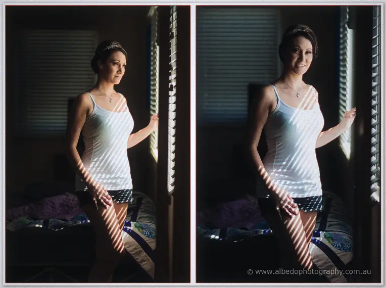Elisha stands at the shutters in her Bride camisole, striped sunlight falling across the bedroom.