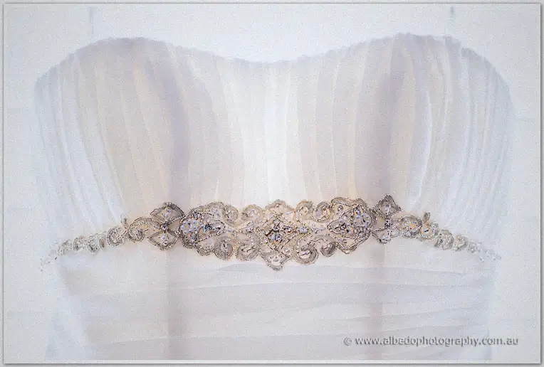 A crystal-beaded belt sparkles across the ruched bodice of Elisha's strapless wedding gown.
