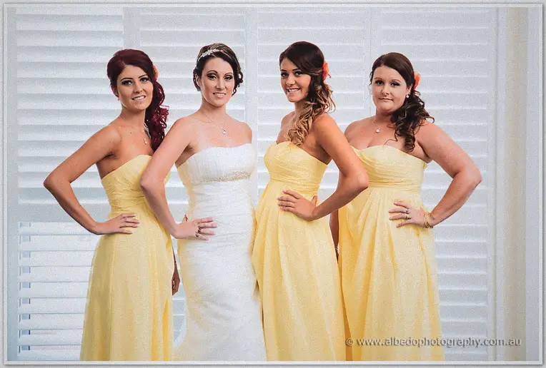 Elisha poses with her four bridesmaids in matching yellow gowns before white shutters