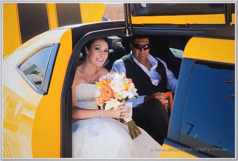 Elisha holds her orange bouquet while seated in the limo beside her father