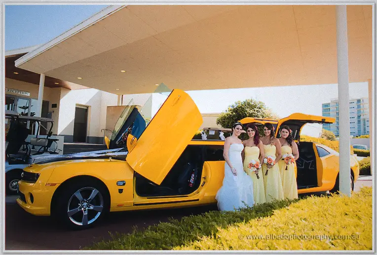 Elisha and her bridesmaids in yellow gather by the open doors of the yellow limo at the clubhouse