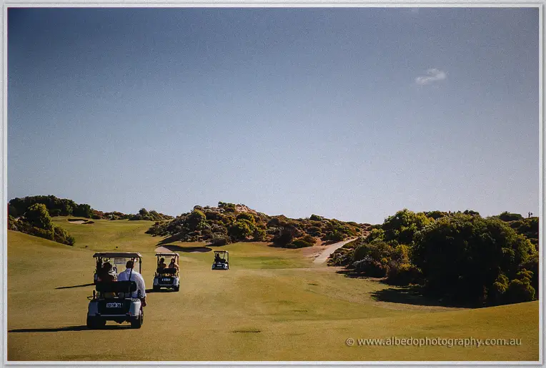 Golf carts carry the wedding party across the wide fairways under a clear blue sky