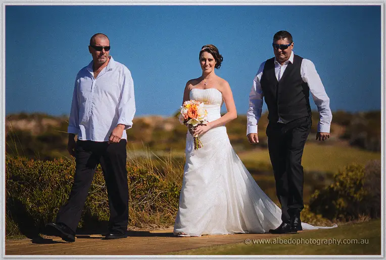 Elisha walks the fairway path flanked by her father and a groomsman