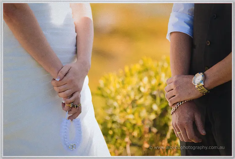 Detail of the couple's hands with the white ring pillow during their vows