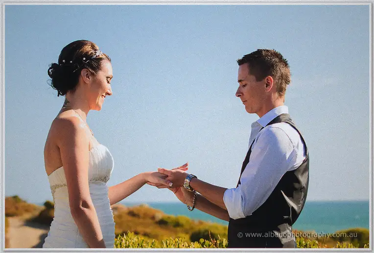 Elisha smiles as Shane places the ring on her finger beside the sea