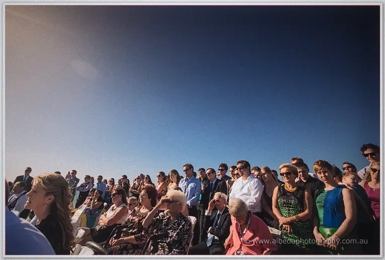 Guests in sunglasses fill the rows beneath a deep blue ceremony sky