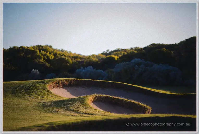Quiet dusk scene of curving sand bunkers and grass at The Cut Dawesville golf course