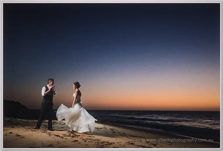 Shane applauds as Elisha swirls her gown on the beach under the deepening dusk
