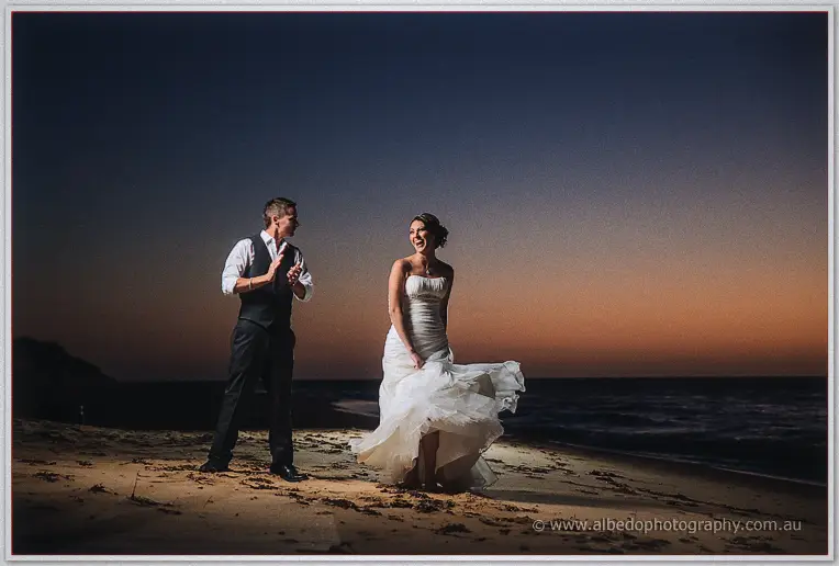 Elisha twirls her dress while Shane claps and grins on the darkening shore