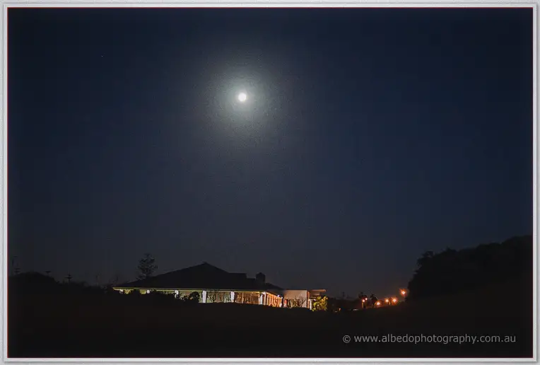 Full moon hangs over the floodlit clubhouse and dark golf course at Dawesville