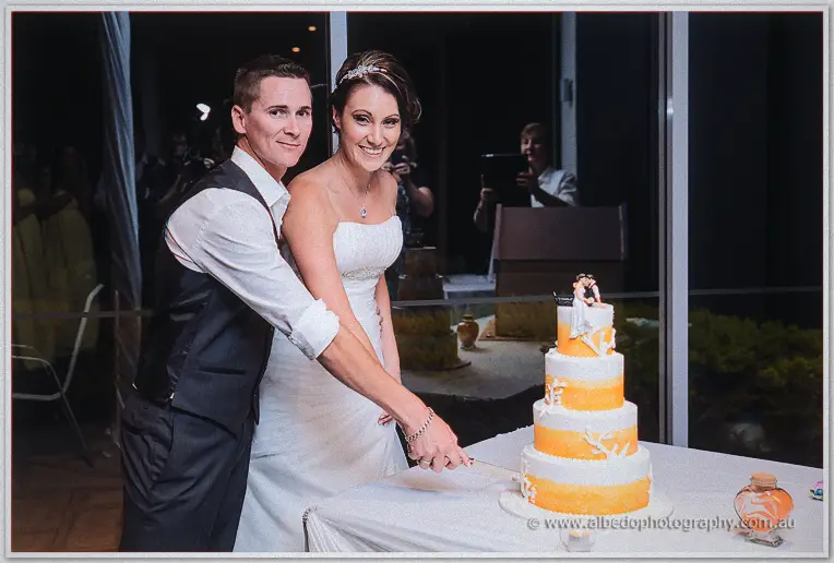 Elisha and Shane cut their four-tier orange and white cake topped with a tiny bride and groom