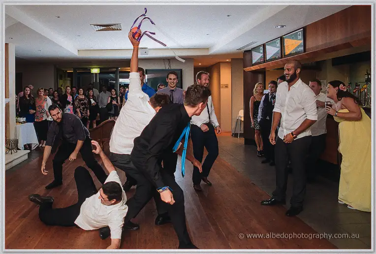 One guest sprawls on the floor as another reaches high above the pack clutching the garter football aloft
