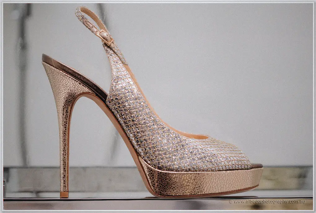 A glittering rose-gold slingback platform heel gleams in profile against soft light