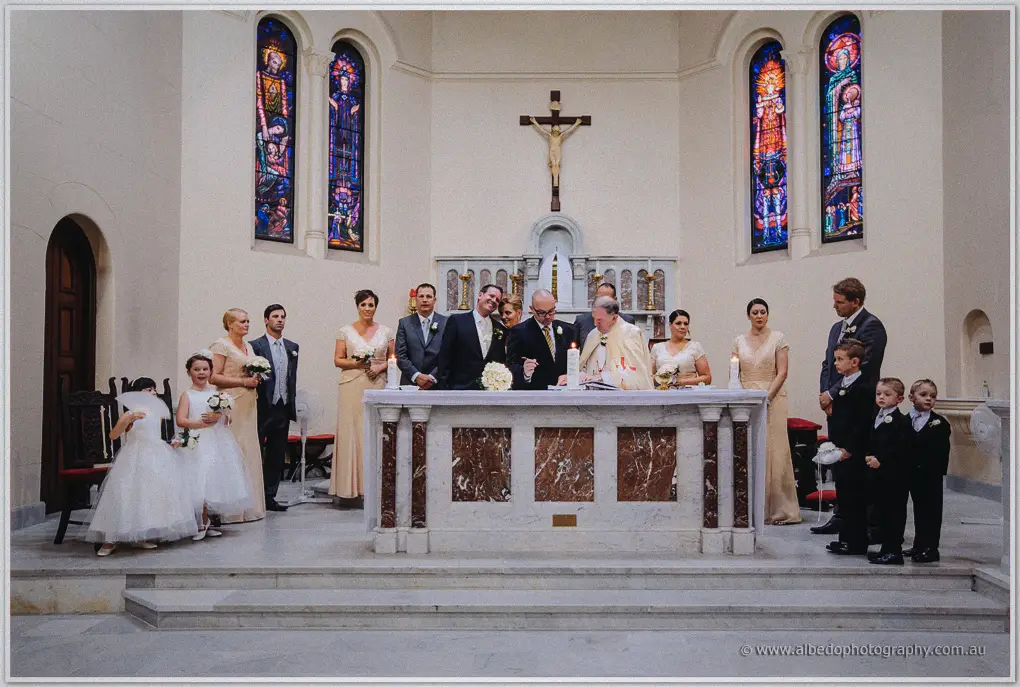 The whole wedding party flanks the marble altar where the priest signs the register