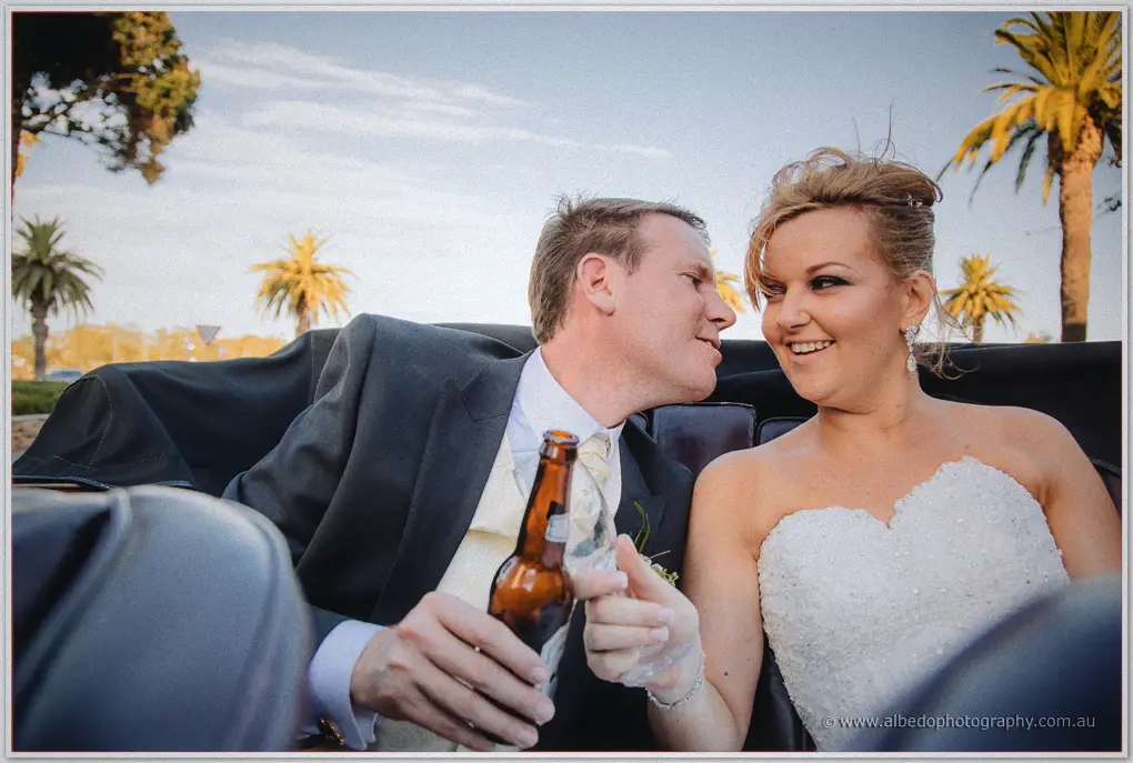 Kristina and Ashley share a beer and a smile in the back of the open-top car at golden hour