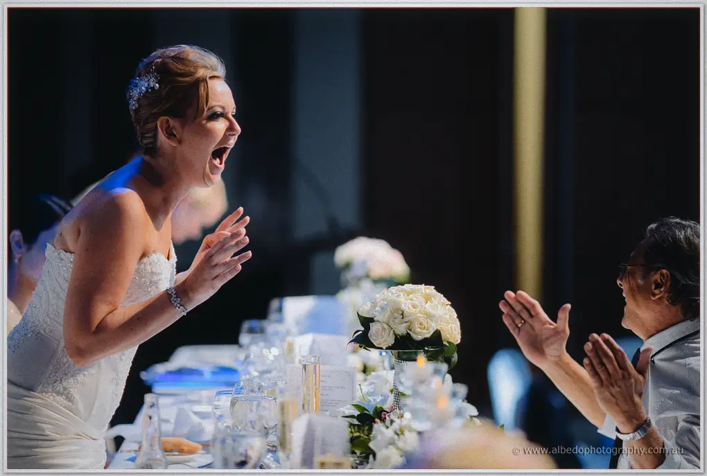Kristina leans across the table laughing as a guest claps back during the speeches