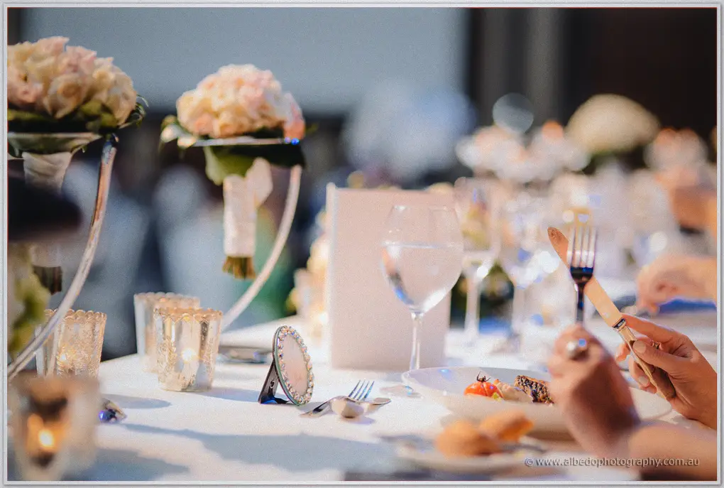 Guests dine among blush bouquets and glowing votive candles on the Astral Ballroom tables