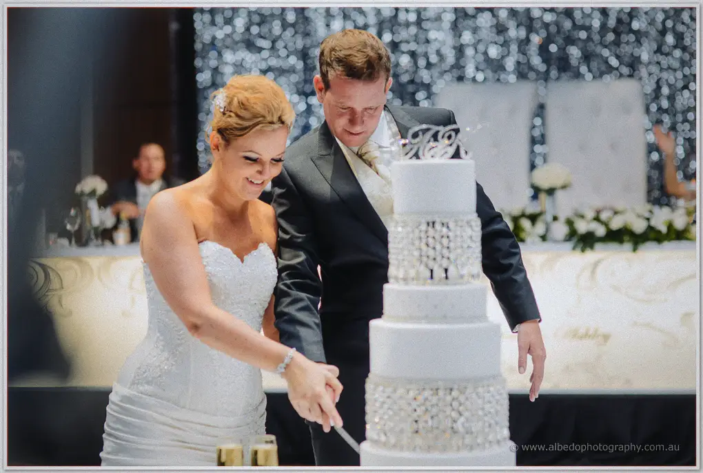 Kristina and Ashley cut their crystal-draped wedding cake before the glittering silver curtain