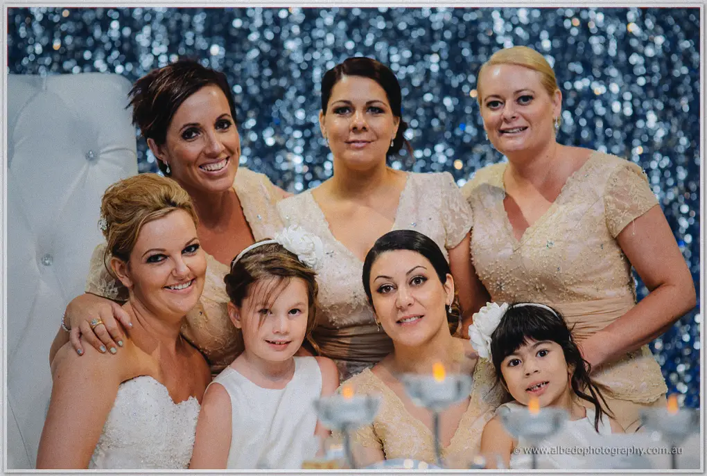 Kristina poses with her bridesmaids and flower girls before the sparkling curtain backdrop