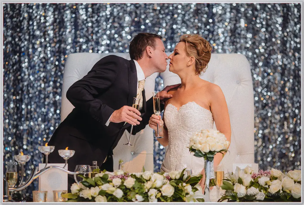 Kristina and Ashley lean in for a kiss over champagne at their throne seats