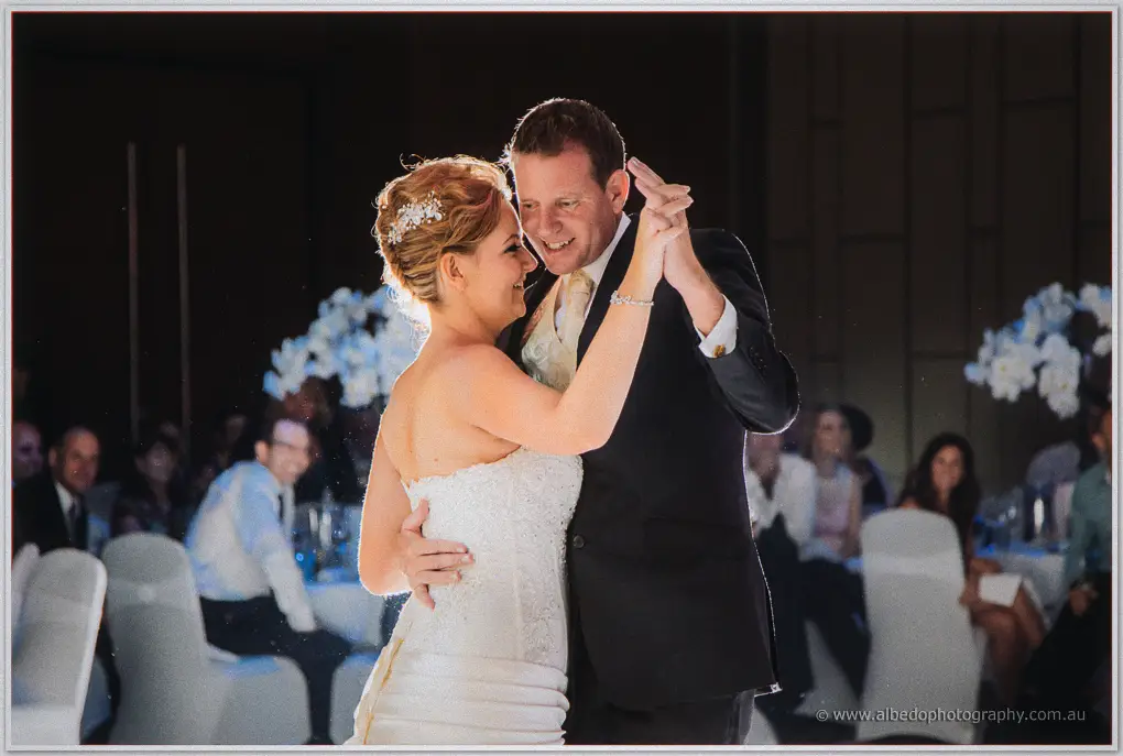 Kristina and Ashley hold each other close as guests watch from candlelit tables