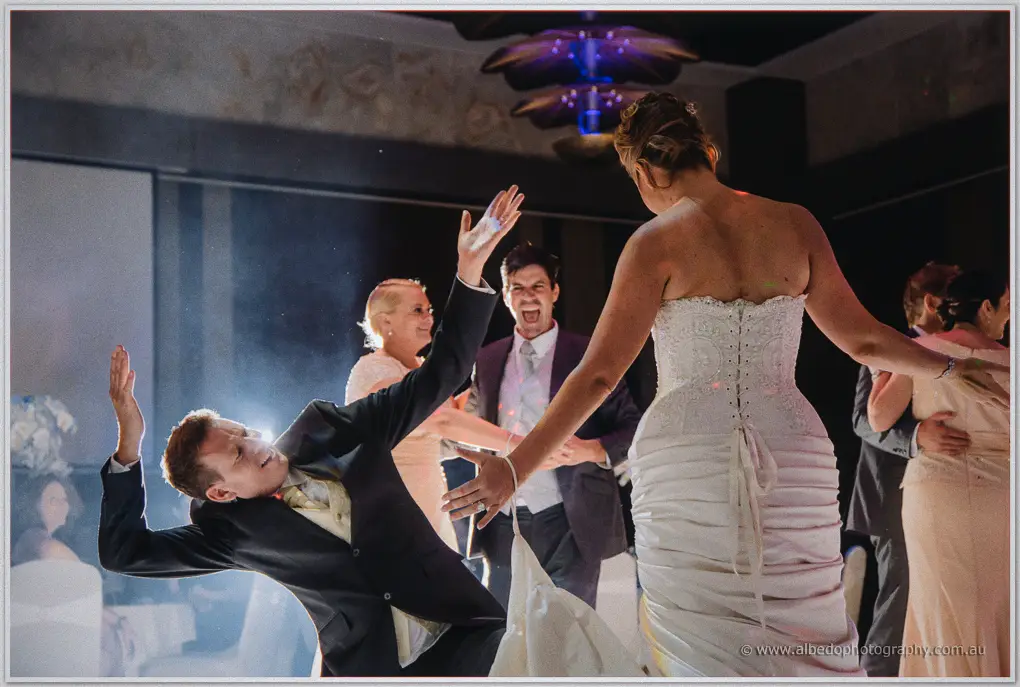 Ashley leans back dramatically on the dance floor as Kristina laughs beside him at their Crown reception.
