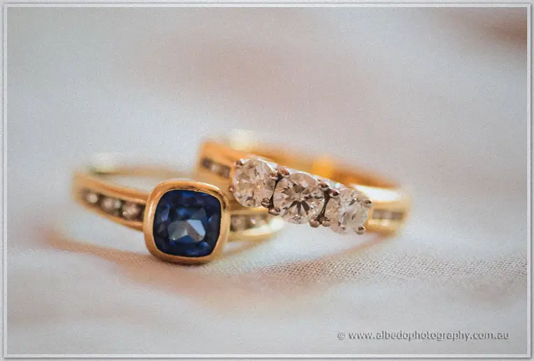Sapphire engagement ring and diamond-set gold band resting on soft white fabric