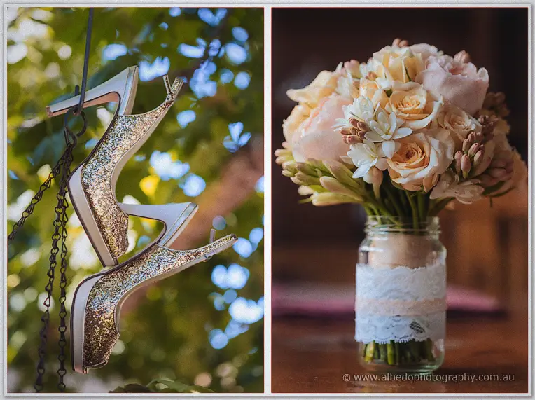 Glittered gold heels hang from a swing beside a peach rose bouquet in a lace-wrapped jar
