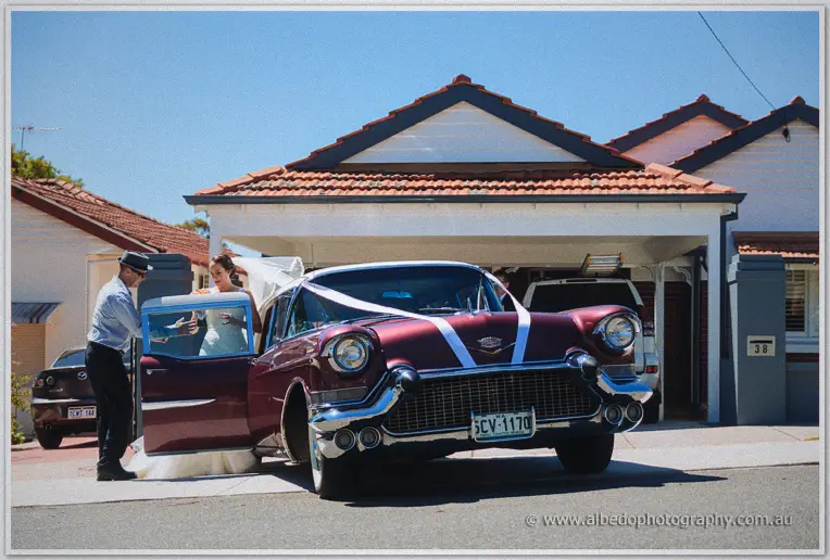 Katelyn steps from a ribbon-tied vintage Cadillac waiting outside a Perth home