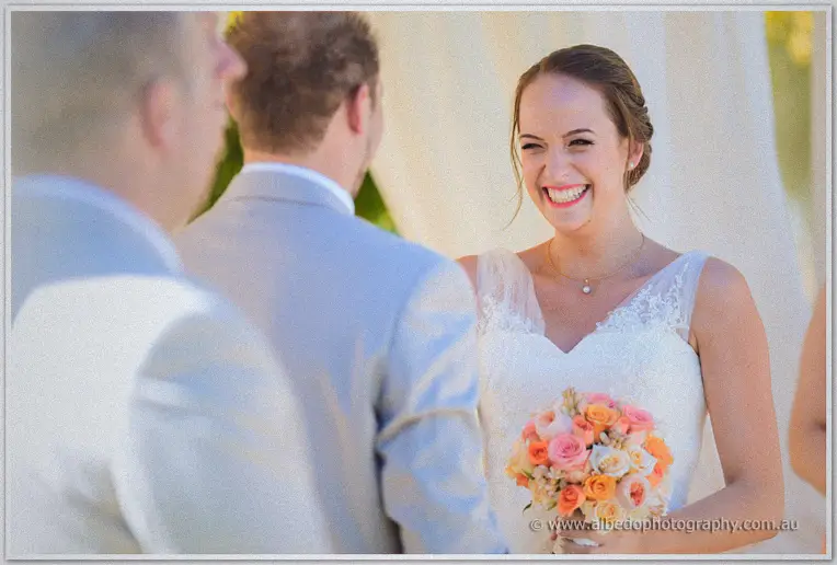 Katelyn beams at Matt beneath the white arbour during their vows