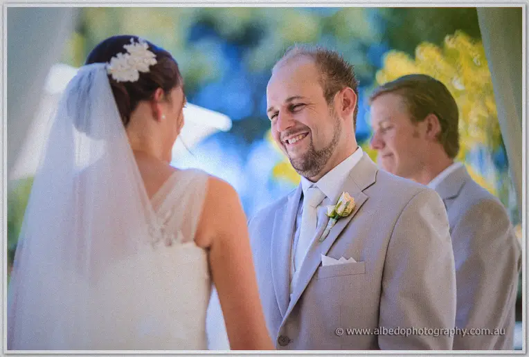 Matt smiles at Katelyn through the vows under the draped gazebo