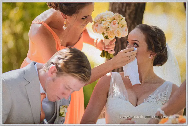 A bridesmaid dries Katelyn's eyes while Matt signs the register