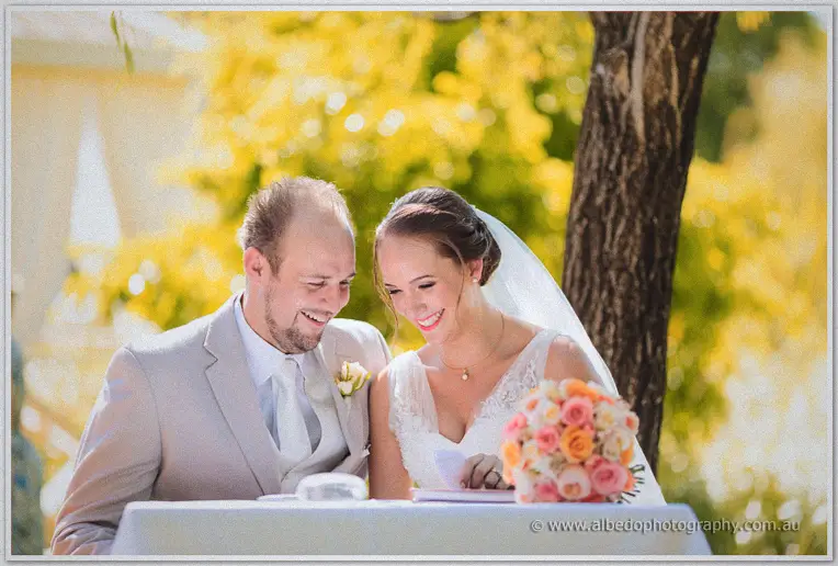 Katelyn and Matt sign the marriage register beneath golden willow leaves