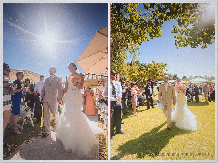 Katelyn and Matt walk back down the aisle through thrown petals in bright sunshine
