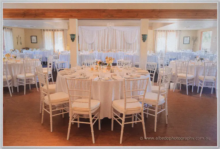 Round guest tables with white chiavari chairs set for the reception in soft window light