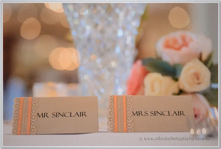 Kraft place cards reading Mr and Mrs Sinclair trimmed with orange ribbon and lace