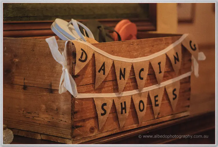 A burlap banner reading dancing shoes hangs on a crate of spare thongs for guests