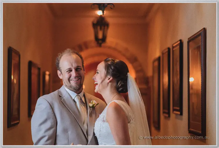 Katelyn straightens Matt's boutonniere in the warm glow of the homestead corridor