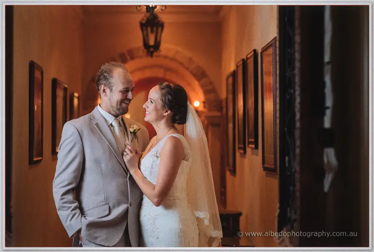 The newlyweds pose beneath wrought-iron lanterns in the wine-cellar hallway