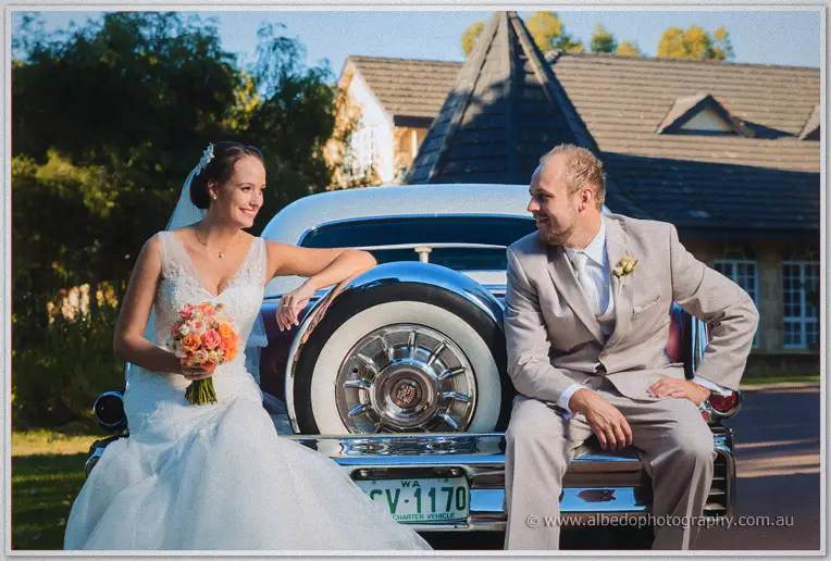 Bride and groom perched on the Cadillac's tail fin, Katelyn resting her arm on the chrome spare wheel