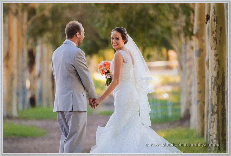 Katelyn grinning back at Matt as she leads him by the hand down the dappled plane-tree avenue