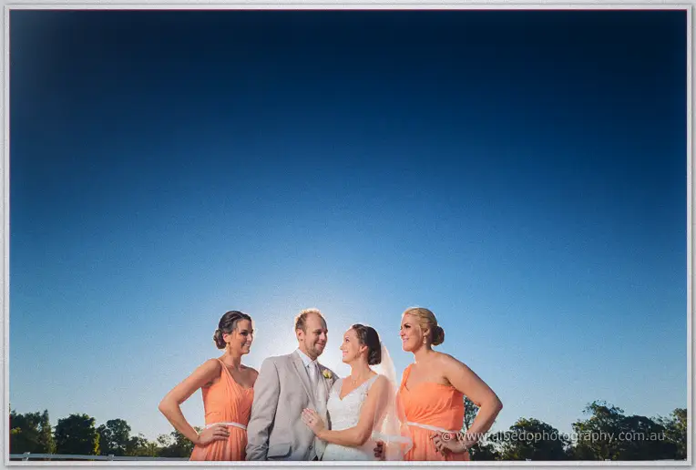 Katelyn flanked by her two bridesmaids with the sun blazing between them at dusk